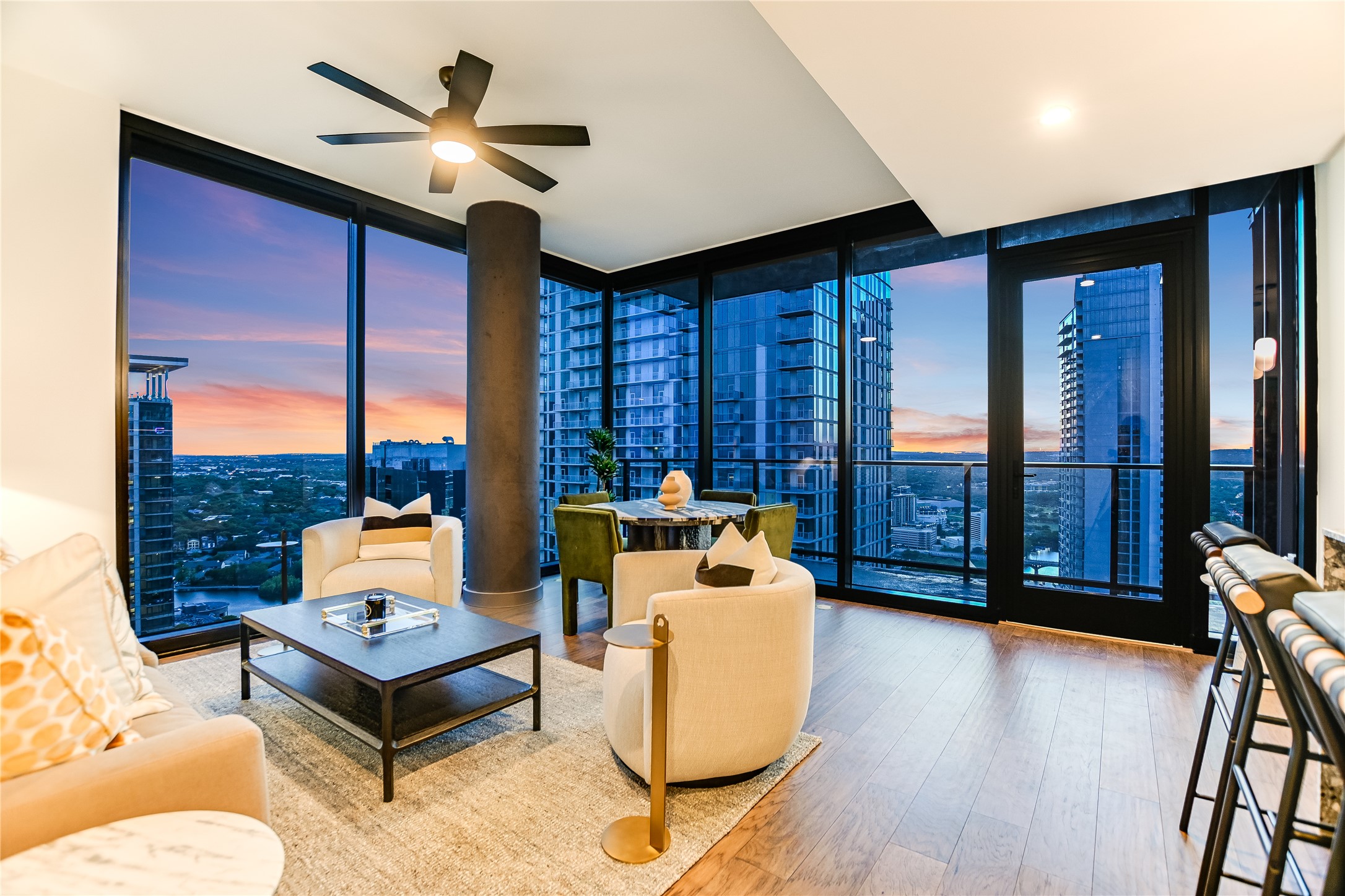 Living room with a city view, expansive windows, hardwood / wood-style floors, and a ceiling fan