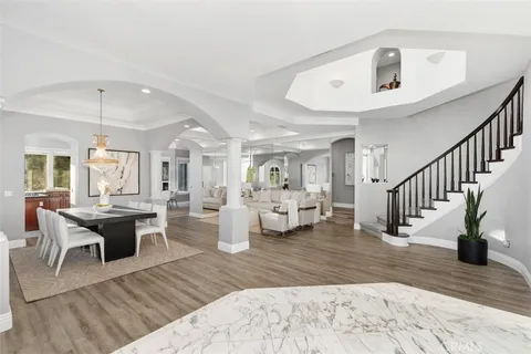 a living room with furniture and a dining table with wooden floor