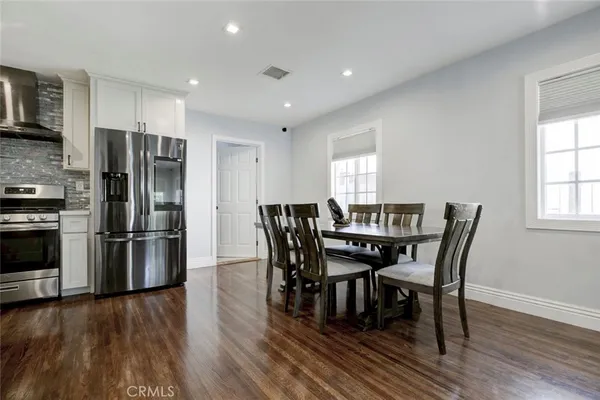 a view of a dining room with furniture a refrigerator and wooden floor