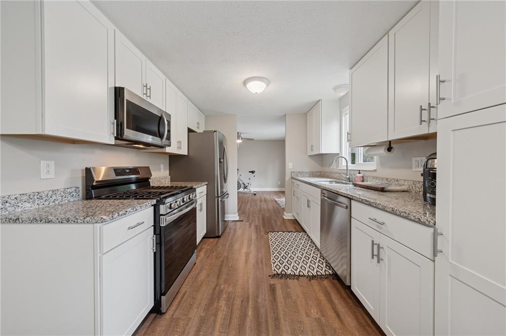 2047 Haymaker Road Monroeville, PA 15146 - Photo 7 of 31 a kitchen with stainless steel appliances granite countertop a stove top oven a sink dishwasher and a refrigerator with wooden floor