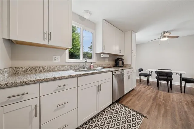 a kitchen with granite countertop a sink a stove cabinets and dining table