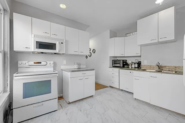 a kitchen with granite countertop white cabinets white stainless steel appliances and sink