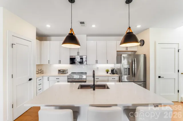 a large kitchen with stainless steel appliances kitchen island a stove a sink a refrigerator a table and chairs