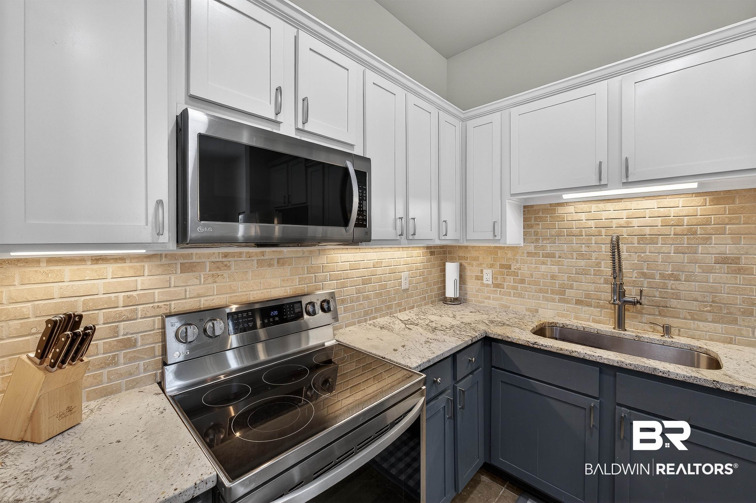 1430 West Regency Road, Unit I102 Gulf Shores, AL 36542 - Photo 8 of 31 Dual tone kitchen with stainless steel appliances, light stone counters, tasteful backsplash, and two tone cabinets