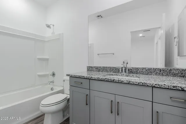 a bathroom with a granite countertop toilet a sink and a bathtub