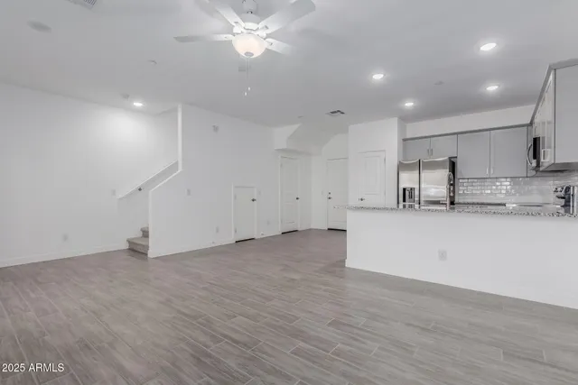 an empty room with wooden floor and stainless steel appliances