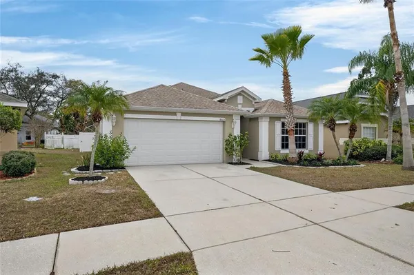 a front view of a house with a yard and palm trees