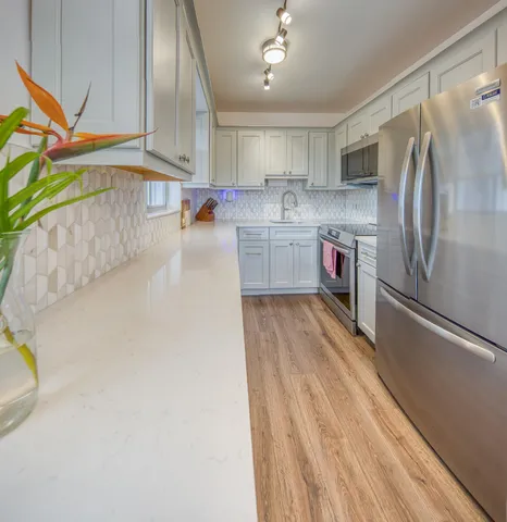 a kitchen with stainless steel appliances a refrigerator sink and white cabinets