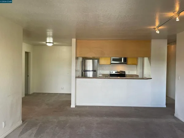 a living room with stainless steel appliances with white cabinets