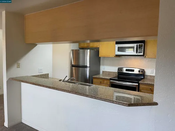a kitchen with granite countertop a refrigerator and a stove top oven