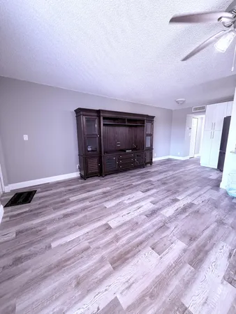 a view of an empty room with window and wooden floor