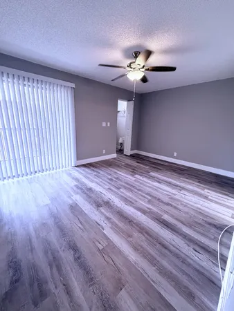 a view of an empty room with a window and a chandelier fan