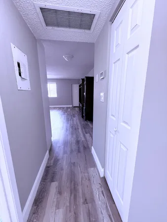 an empty room with wooden floor chandelier fan and windows