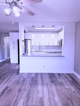 a view of empty room with kitchen and window