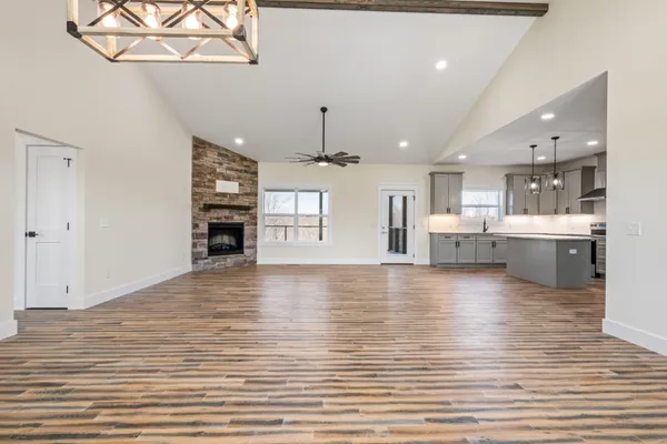 a view of a room with wooden floor fireplace and windows