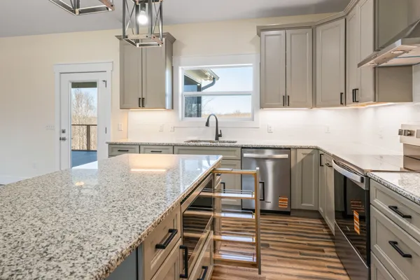 a kitchen with stainless steel appliances granite countertop a sink a stove and a wooden floors
