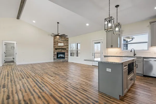 a kitchen with stainless steel appliances granite countertop a refrigerator a stove and a wooden floors