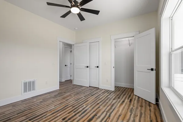 a view of an empty room with wooden floor and a window