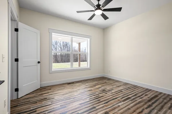 a view of a room with wooden floor and a ceiling fan