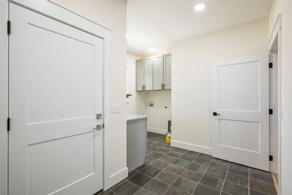 an empty room with wooden floor chandelier and windows