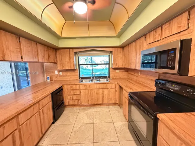 a kitchen with stainless steel appliances granite countertop a stove a sink dishwasher and a microwave oven with white cabinets