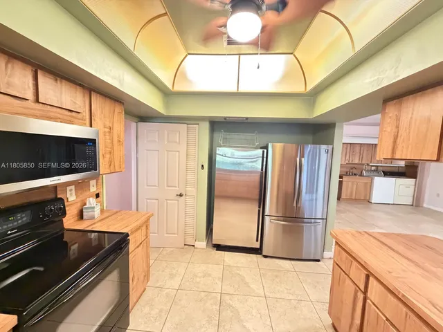 a kitchen with stainless steel appliances kitchen island granite countertop a refrigerator and a stove top oven