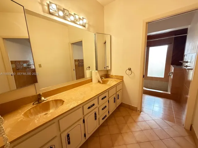 a spacious bathroom with a double vanity sink a mirror and a bathtub