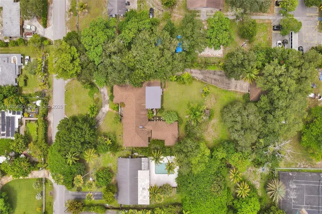 an aerial view of residential houses with outdoor space and trees all around