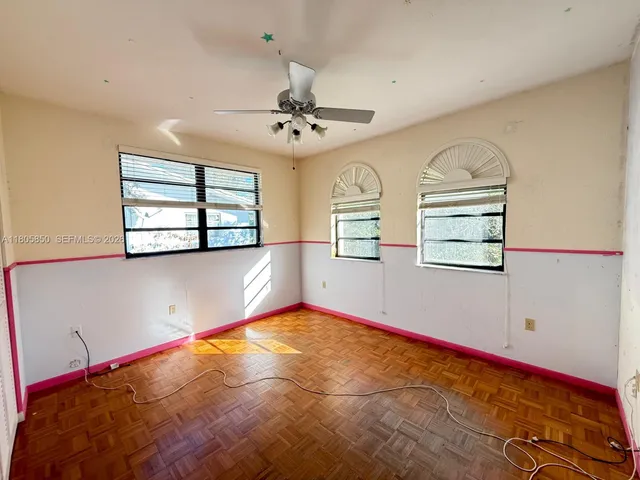 an empty room with windows and ceiling fan