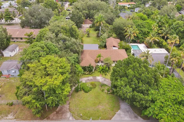 an aerial view of a house with a yard and large trees
