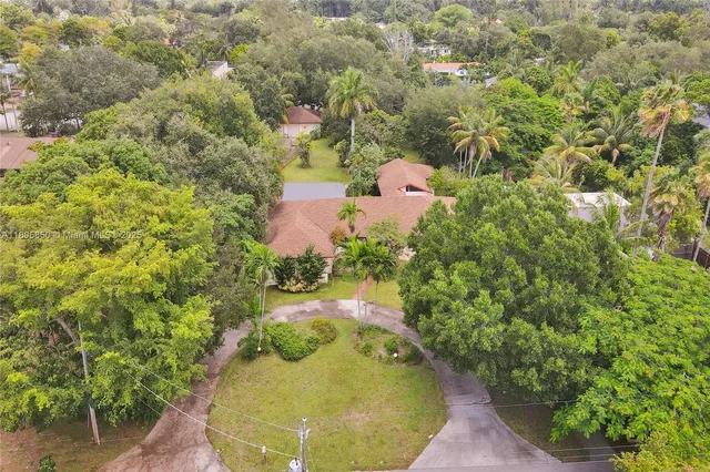 an aerial view of a house with a yard and large tree
