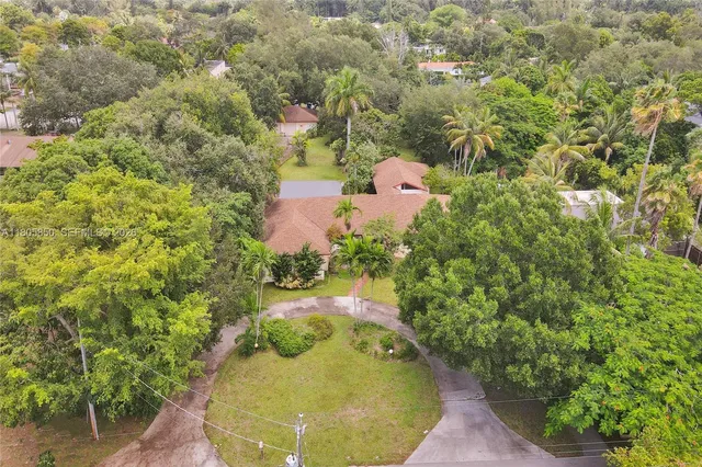 an aerial view of a house with a yard and large tree