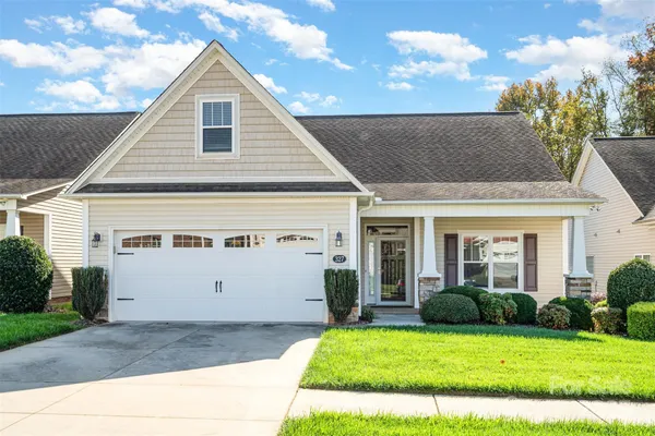 a view of a white house next to a yard with potted plants