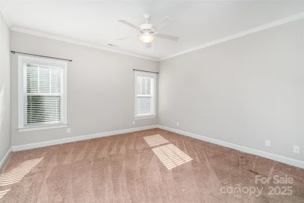an empty room with windows and ceiling fan