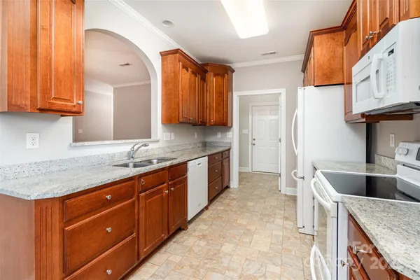 a kitchen with granite countertop a sink a stove and cabinets