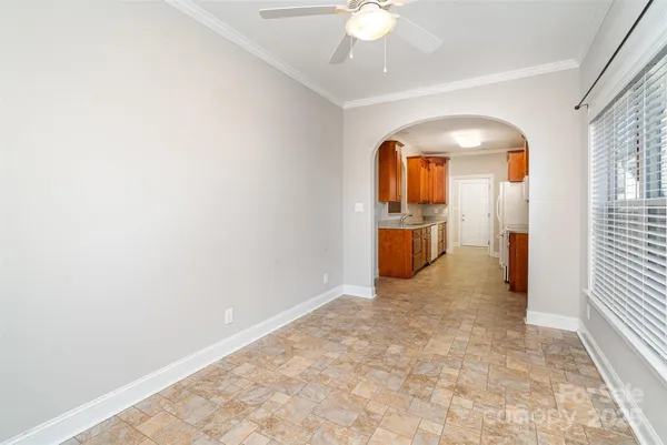 an empty room with chandelier fan and wooden floor