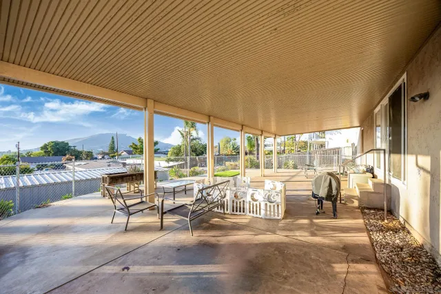 a view of a patio with lawn chairs potted plants and floor to ceiling window