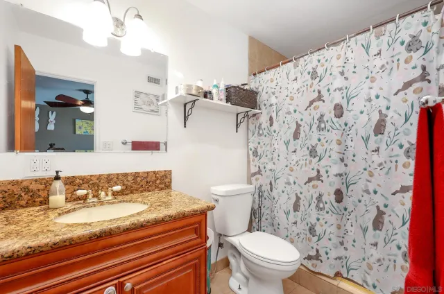 a bathroom with a granite countertop toilet sink mirror and shower