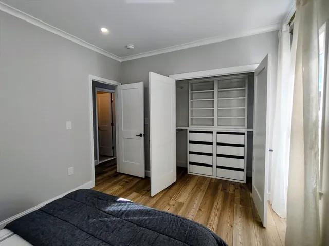 a view of a bedroom with wooden floor and closet