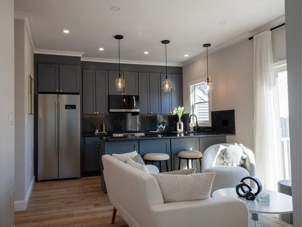 a living room with stainless steel appliances kitchen island granite countertop furniture a refrigerator a sink a stove and a microwave