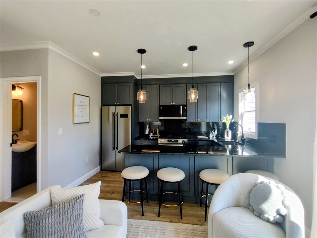 93 Grove Street, Unit 1R Fall River, MA 02720 - Photo 6 of 21 a kitchen with stainless steel appliances kitchen island granite countertop a refrigerator a sink a stove a dining table and chairs with wooden floor