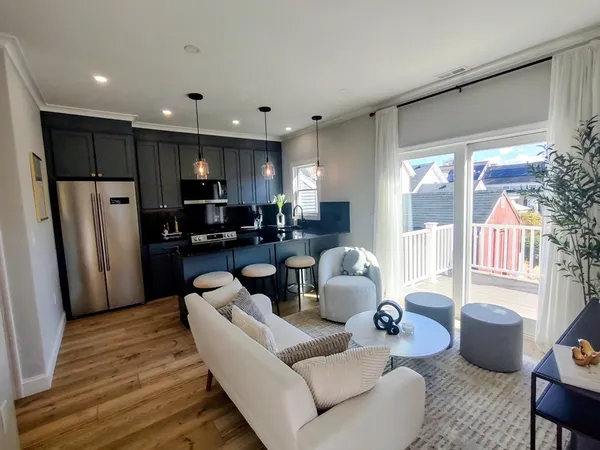 a living room with furniture kitchen view and a large window