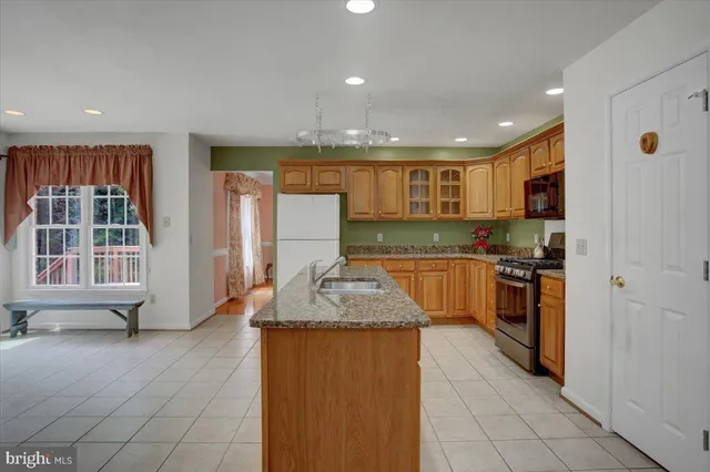 a kitchen with kitchen island granite countertop a stove sink and cabinets