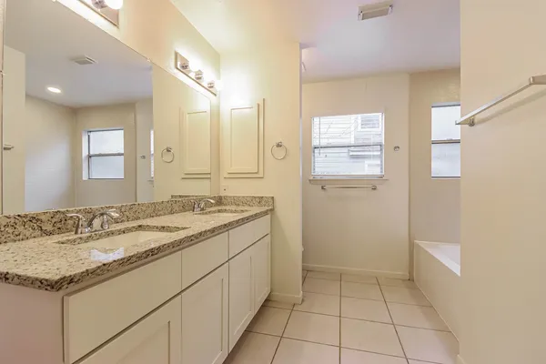 a bathroom with a granite countertop sink a mirror and a shower