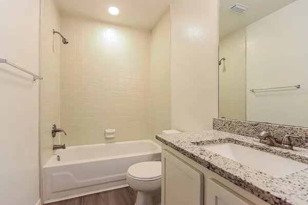 a bathroom with a granite countertop sink a toilet and bathtub