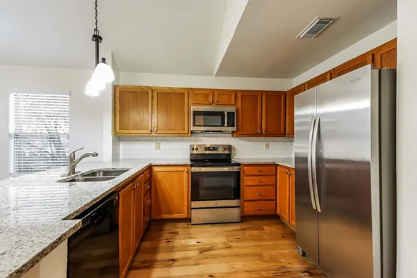 a kitchen with stainless steel appliances granite countertop a sink stove and refrigerator