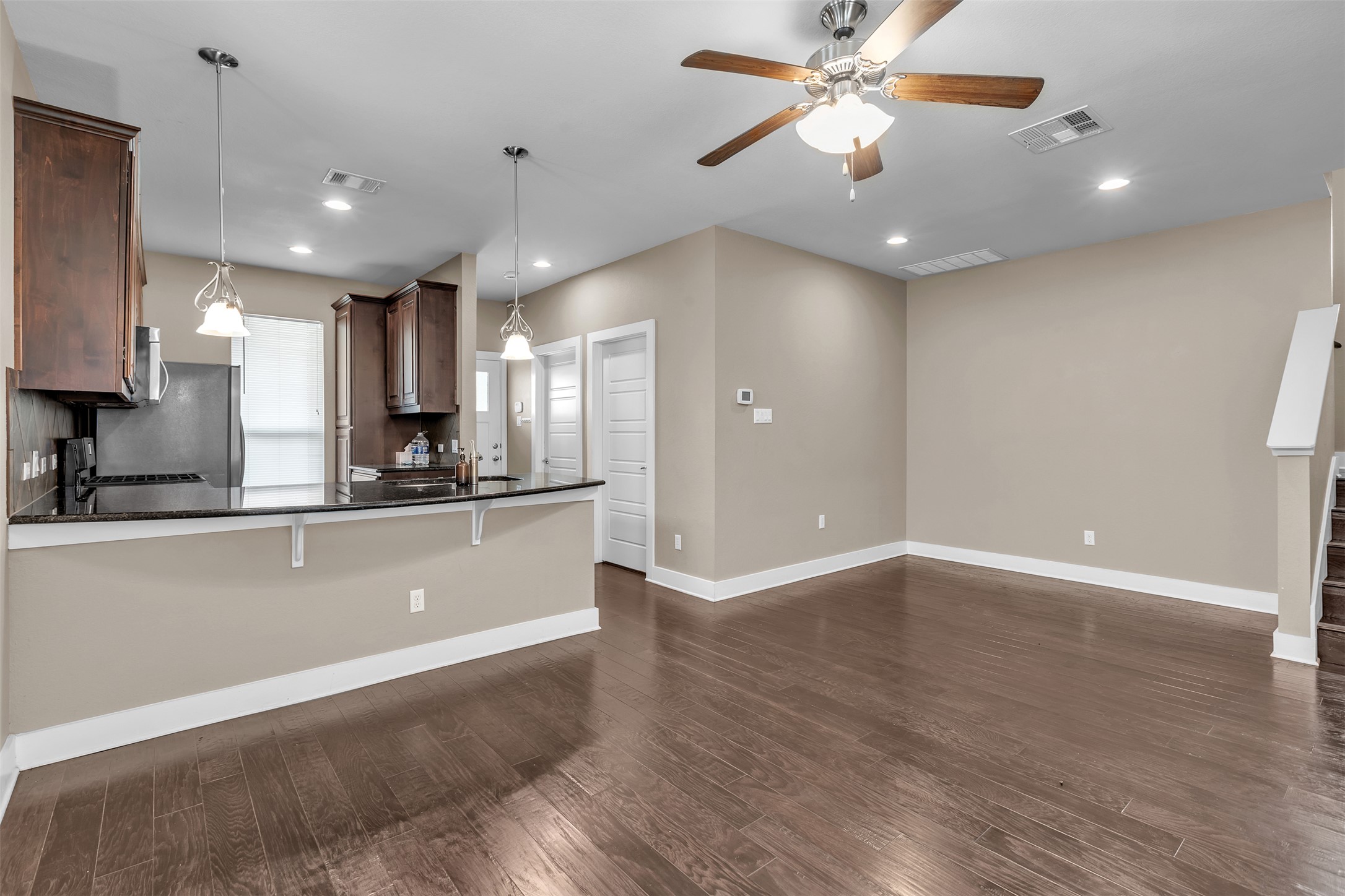 12212 Tawny Farms Road, Unit 142 Austin, TX 78748 - Photo 6 of 21 Rich hardwood floors flow through an open-concept living area and into a contemporary kitchen, ideal for daily living.