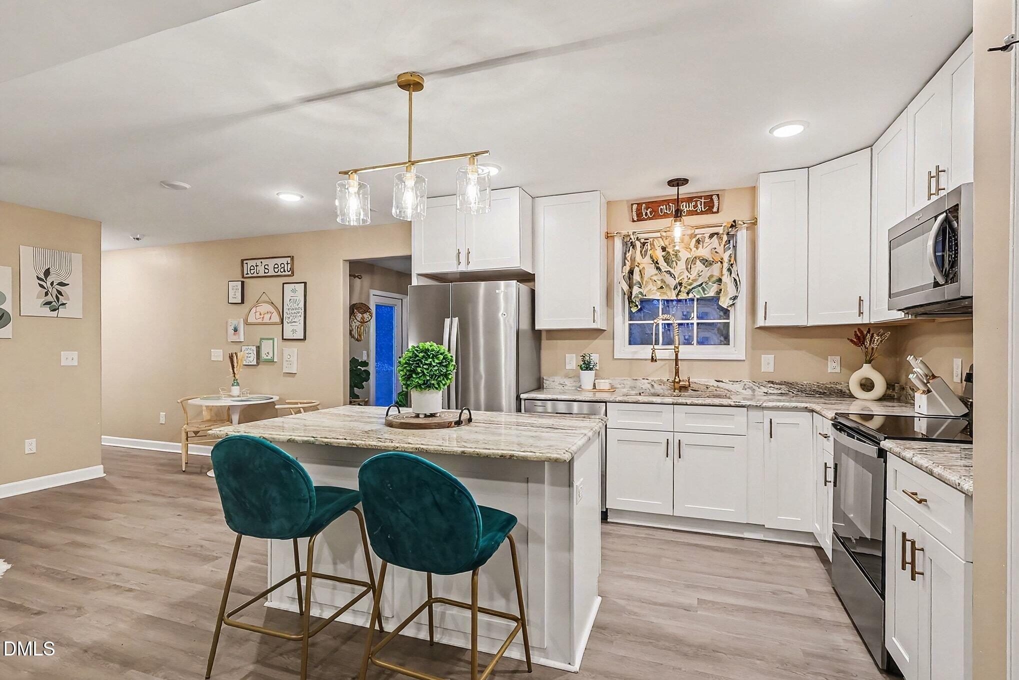 115 Southern High School Road Graham, NC 27253 - Photo 13 of 34 a kitchen with stainless steel appliances granite countertop a sink a stove a refrigerator a microwave oven with white cabinets and wooden floor