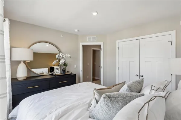 a bedroom with a bed and a lamp on dresser