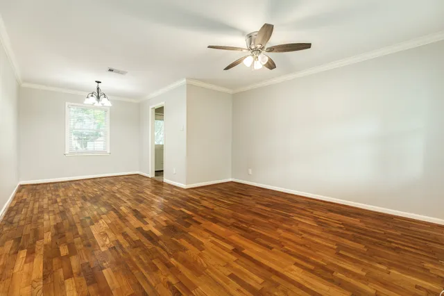 a view of empty room with wooden floor and fan